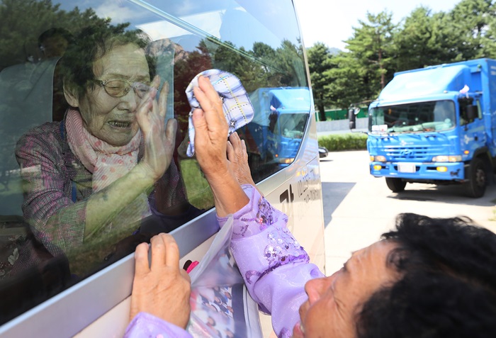  
南北離散家族再会行事が終わり、韓国に戻るバスに乗って、北朝鮮の娘と別れの挨拶をしながら涙を流す韓国のハン・シンジャ氏（左）＝２２日、北朝鮮・金剛山

