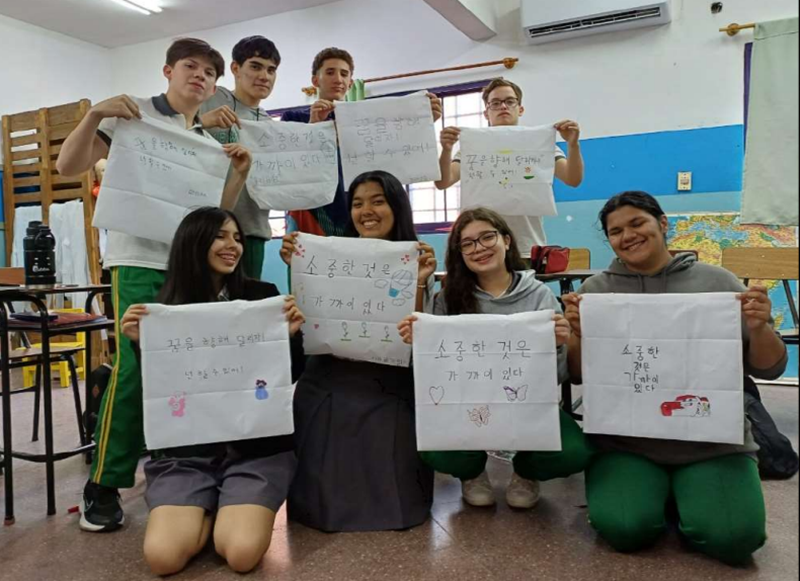 書道の授業で書いたハングルを手に、笑顔で記念撮影をするパラグアイの学生たち＝教育部