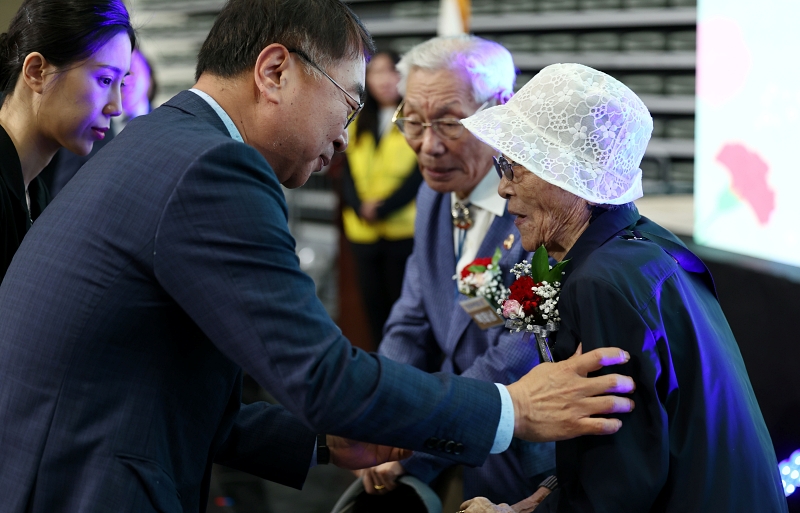 ８日、ソウル市内で開催された「父母の日（両親の日）」の記念式典で、キム・サンハン（左）ソウル市行政１副市長がお年寄りの方の胸元にカーネーションを飾っている。 