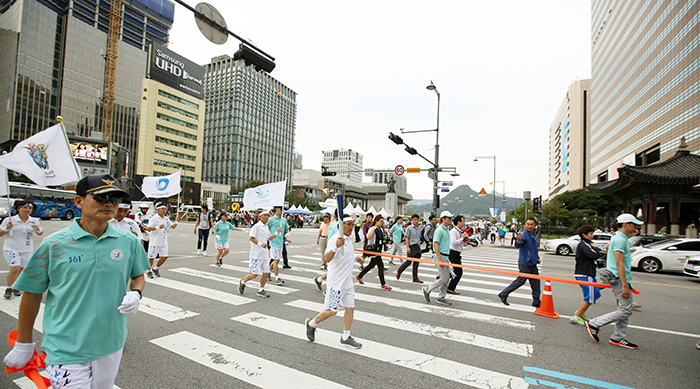 인천 아시아경기대회 성화봉송 참가자가 16일 세종대로를 거쳐 종로로 향하고 있다. 