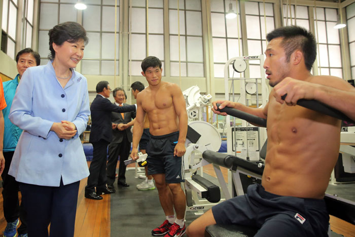 2014仁川アジア競技大会の開幕まであと25日と迫った8月25日午後、ソウル蘆原区の太陵選手村を訪れたパク大統領(左)がレスリング韓国代表の選手たちを激励している(写真提供：聯合ニュース)