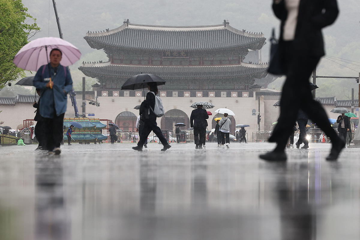  １５日午前、ソウル・光化門（クァンファムン）広場で傘をさして歩く市民たち。
