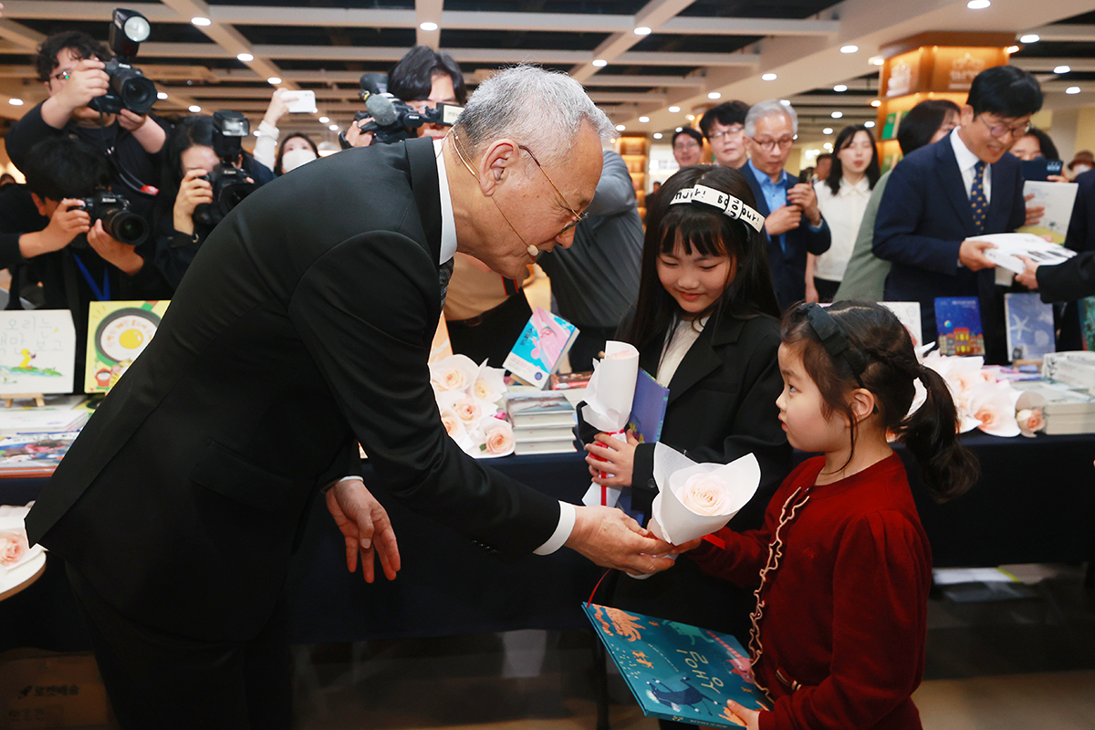 ２３日、「世界本の日」を迎え、ソウル市内の世宗文化会館で行われた行事で、文化体育観光部の柳仁村長官が子どもに本をプレゼントしている。 