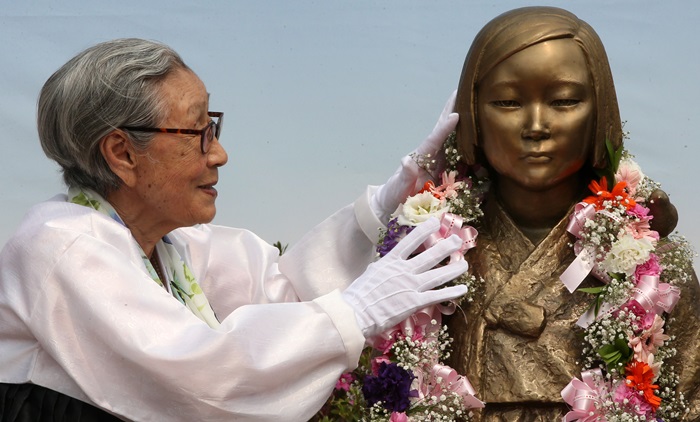２０１４年４月、京畿道の城南市に設置されている「平和の少女像」をなでる金福童さん＝聨合ニュース