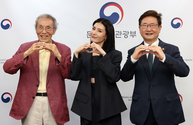 記念撮影する（左から）俳優オ・ヨンス氏、振付師モニカ氏、文化体育館後部の朴普均長官＝２５日、ソウル