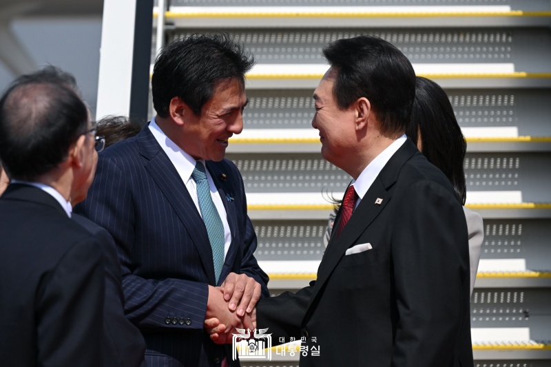 １６日、東京・羽田空港に到着した尹大統領（右）が、武井俊輔外務副大臣（左から２番目）と握手している＝１６日、日本・東京