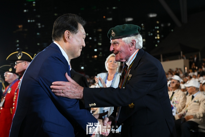 （左）休戦協定７０周年の式典で参戦勇士と握手する尹大統領＝２７日、釜山