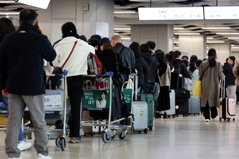 昨年、国内線と国際線の航空旅客数が４年ぶりに１億人を超えた。写真は、金浦空港の国内線で搭乗手続きのために並ぶ旅行客の様子＝２０２３年１２月２９日、ソウル、 聯合ニュース