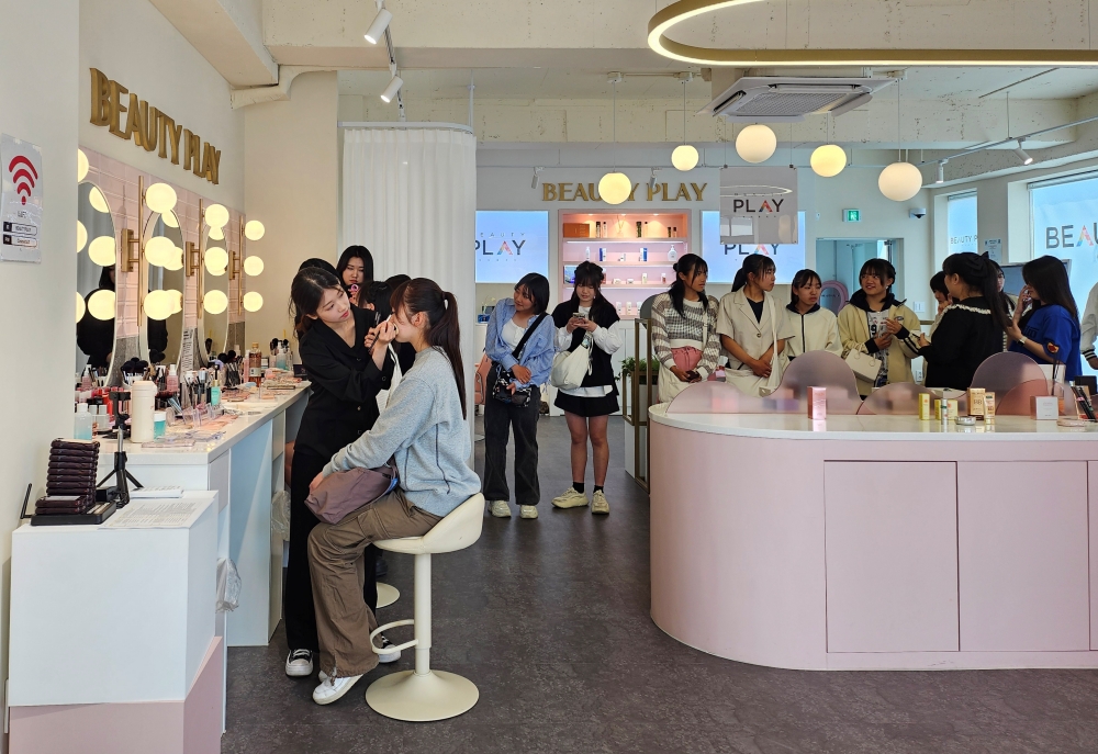 写真は、ビューティープレイ弘大店でメイク体験をしている外国人観光客の様子＝２０２４年５月、KOREA.net DB