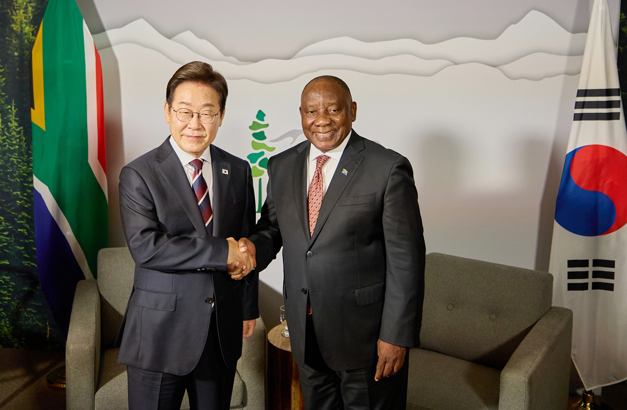 南アフリカ共和国のシリル・ラマポーザ大統領と握手をするイ・ジェミョン大統領（左）＝１６日（現地時間）、カナダ