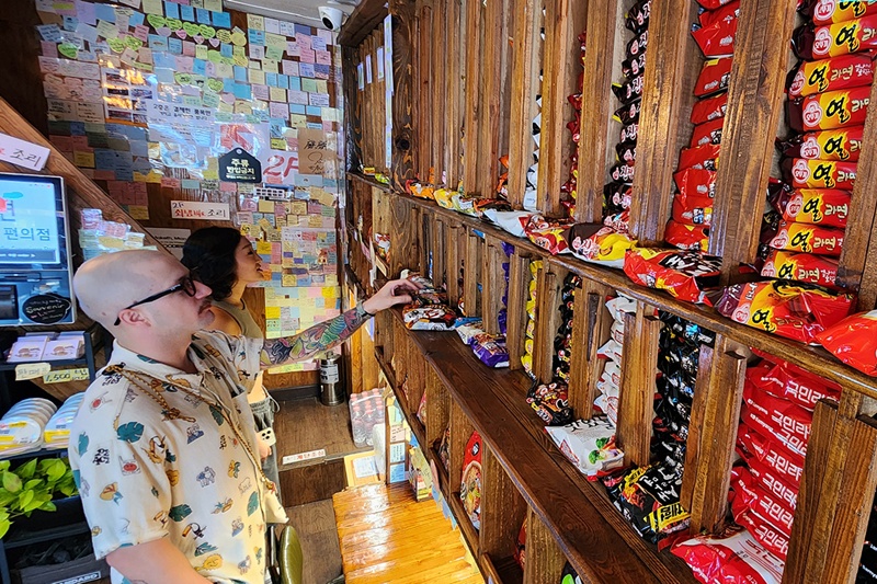 写真は、コンビニでラーメンを選ぶ外国人の様子＝２０２４年８月６日、ソウル、聯合ニュース