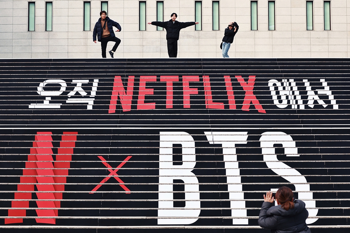 写真は、世宗文化会館の階段で、ＢＴＳのラッピングを背景に記念撮影を行う外国人観光客＝１１日、ソウル、聯合ニュース