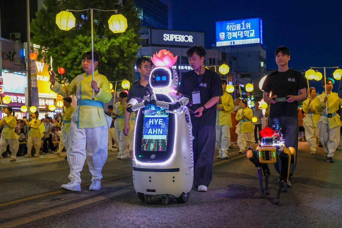 仏教行事「燃灯会」で行列の先頭に立つＡＩロボット僧侶「ヒェアン」（左）と、巡回・安全用の四足歩行ロボット「グーギー」＝１６日、ソウル