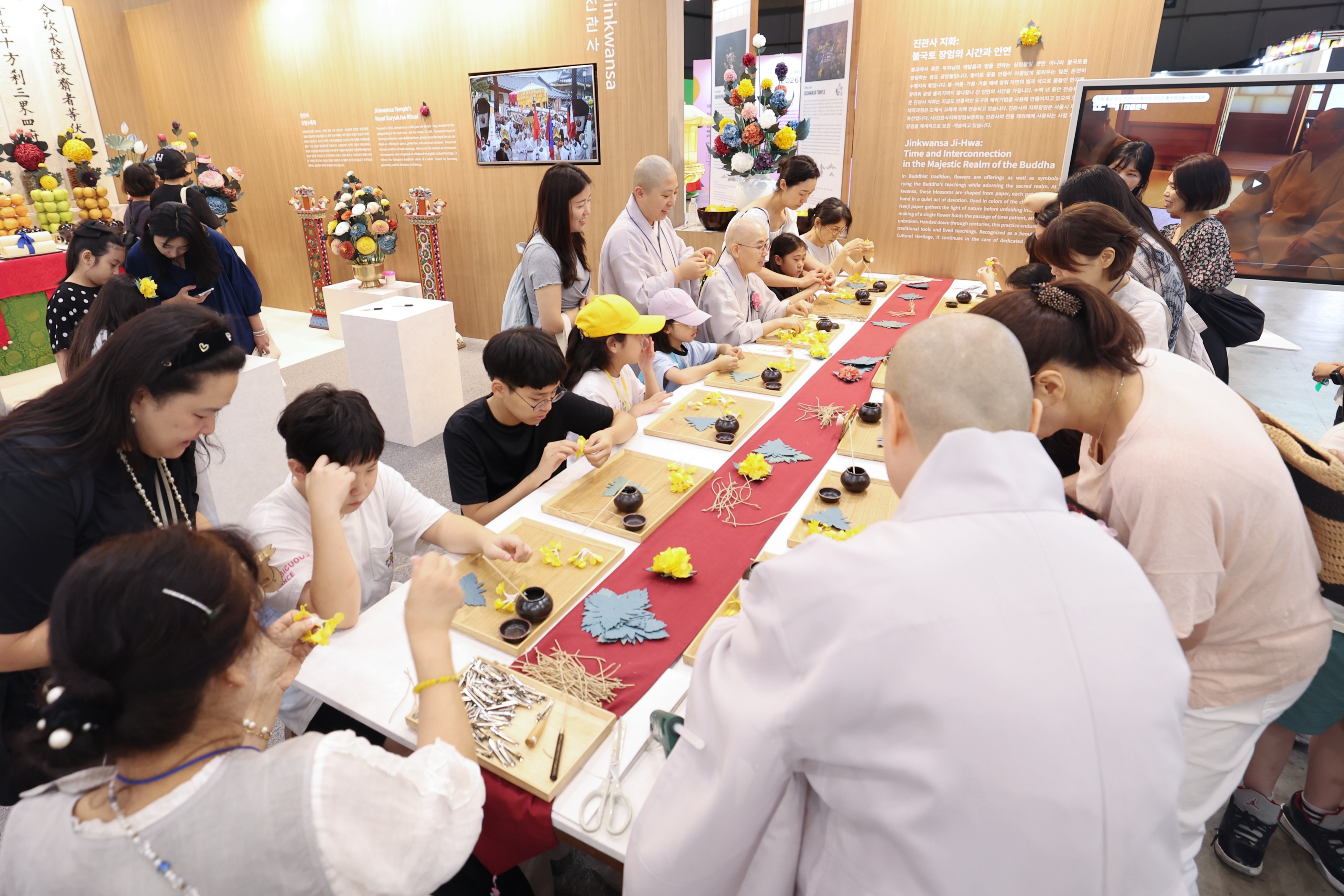 大韓民国館にある津寛寺のブースで、伝統紙の花「紙花」作りを体験する観覧客＝２３日、釜山