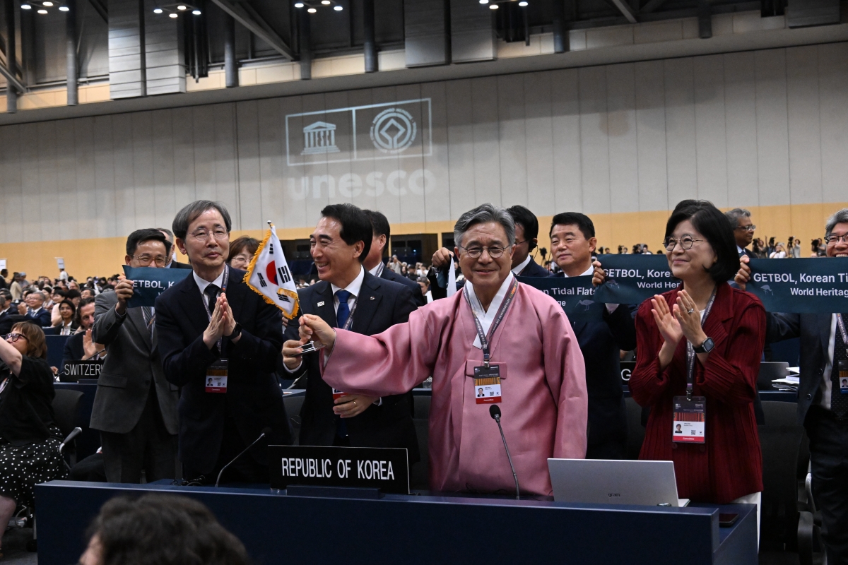 「韓国の干潟（第２段階）」の拡大登録決定を受け、喜びを分かち合う国家遺産庁のホ・ミン庁長（右から２人目）と駐ユネスコ韓国代表部のキム・ジヒ大使（右端）ら韓国政府代表団＝２５日、釜山、国家遺産庁