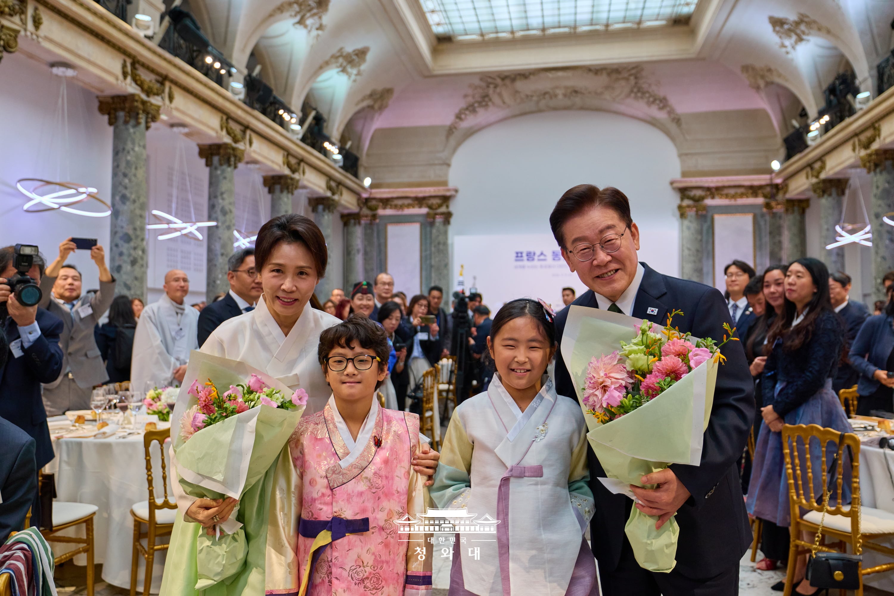 在仏韓国人との昼食懇談会で、花束を手に記念撮影を行う李大統領夫妻＝９日、フランス・パリ