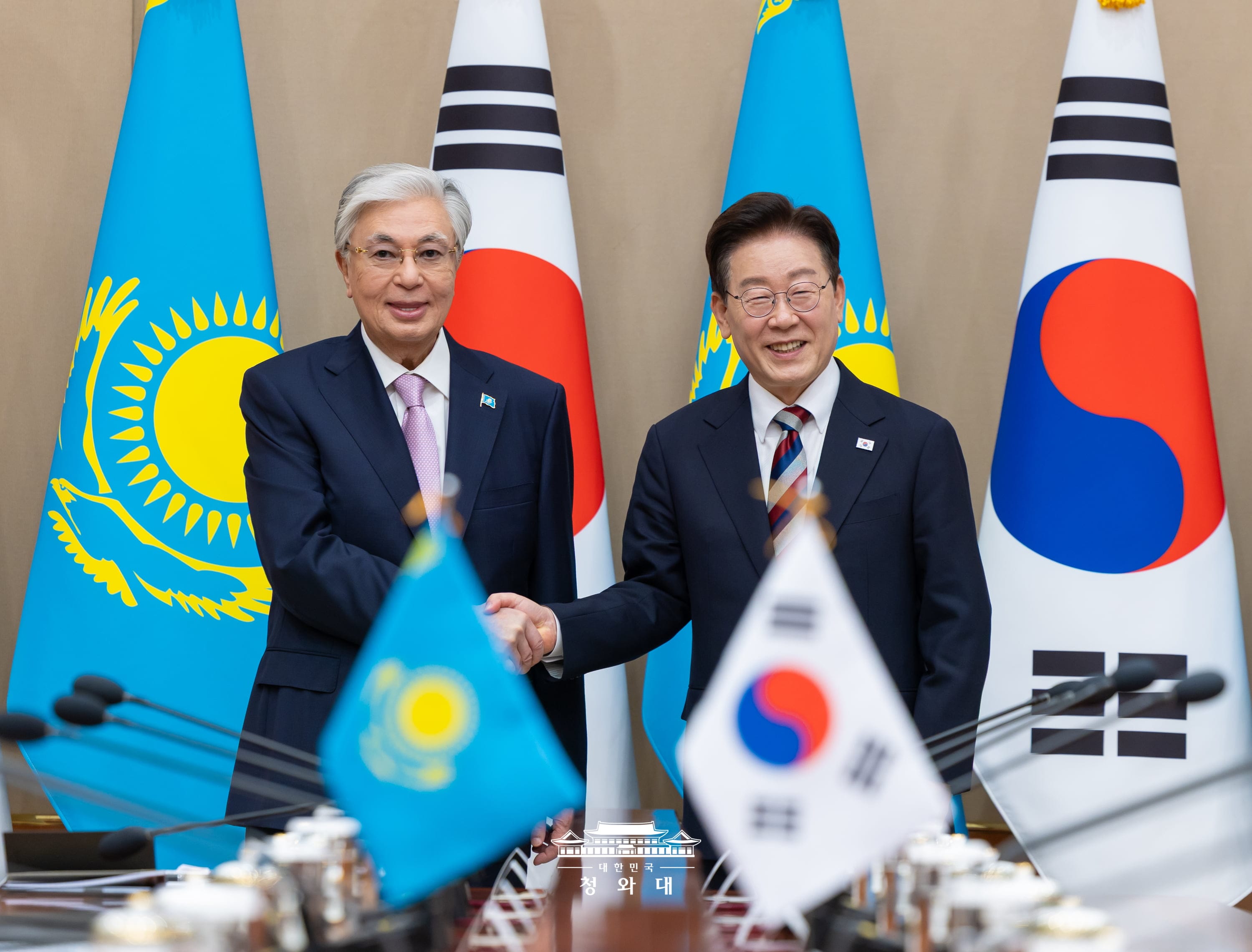 拡大首脳会談を前に握手を交わす李在明大統領（右）とカザフスタンのカシムジョマルト・トカエフ大統領＝１５日、ソウル