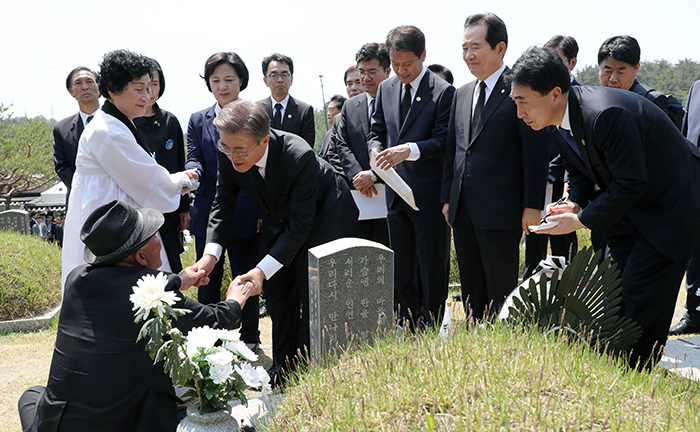 文在寅大統領が18日、光州国立5.18国立墓地にて遺族の手を握って慰労の言葉を伝えている。