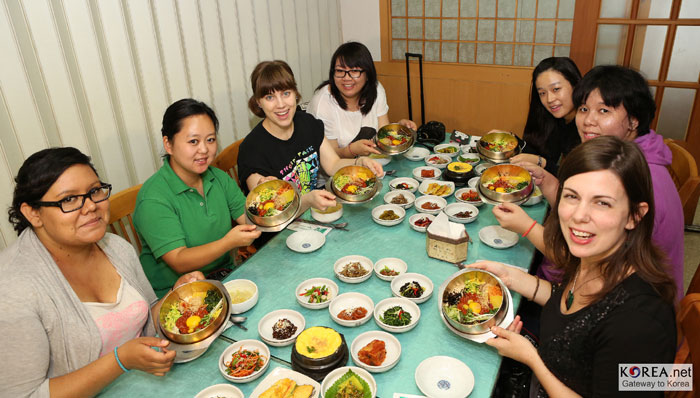 ビビンバは、外国人も好んで食べる韓国料理だ。入れる材料の種類と混ぜ具合によってそれぞれ好みに合わせて作ることができ、多様な食材が織りなす味の調和を楽しむことができる。写真はビビンバを食べている外国人留学生たち