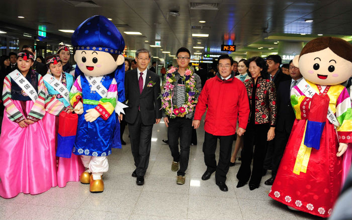  2013년 12월 27일 제주공항 국제선 입국장에서 조현재 문화체육관광부차관(왼쪽에서 네 번째)이 1,200만번째 입국자인 중국 관광객 마 지아오(Ma Jiao, 중간)씨에게 화환을 증정하고 외국인관광객 1천2백만명 돌파를 축하하고 있다. (사진: 문화체육관광부) 