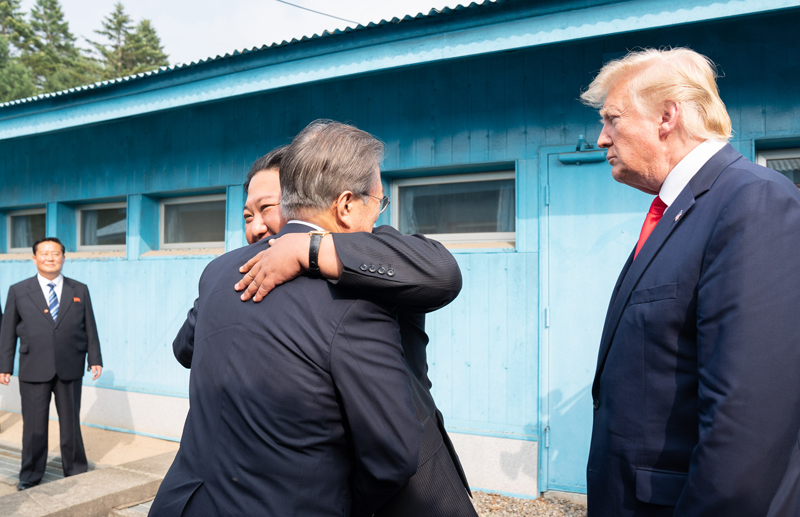 ハグする文在寅大統領（左）と北朝鮮の金正恩朝鮮労働党委員長。二人を見守る米国のトランプ大統領＝６月３０日、板門店、ホワイトハウス