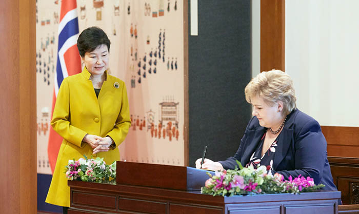 朴槿恵大統領(左)が見守るなか、ノルウェーのエルナ・ソルベルグ首相が芳名録に署名をしている 