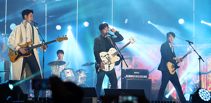CNBLUEの公演中にメンバーのチョン・ヨンファがファンに向かってピースサインを作りウィンクしている
