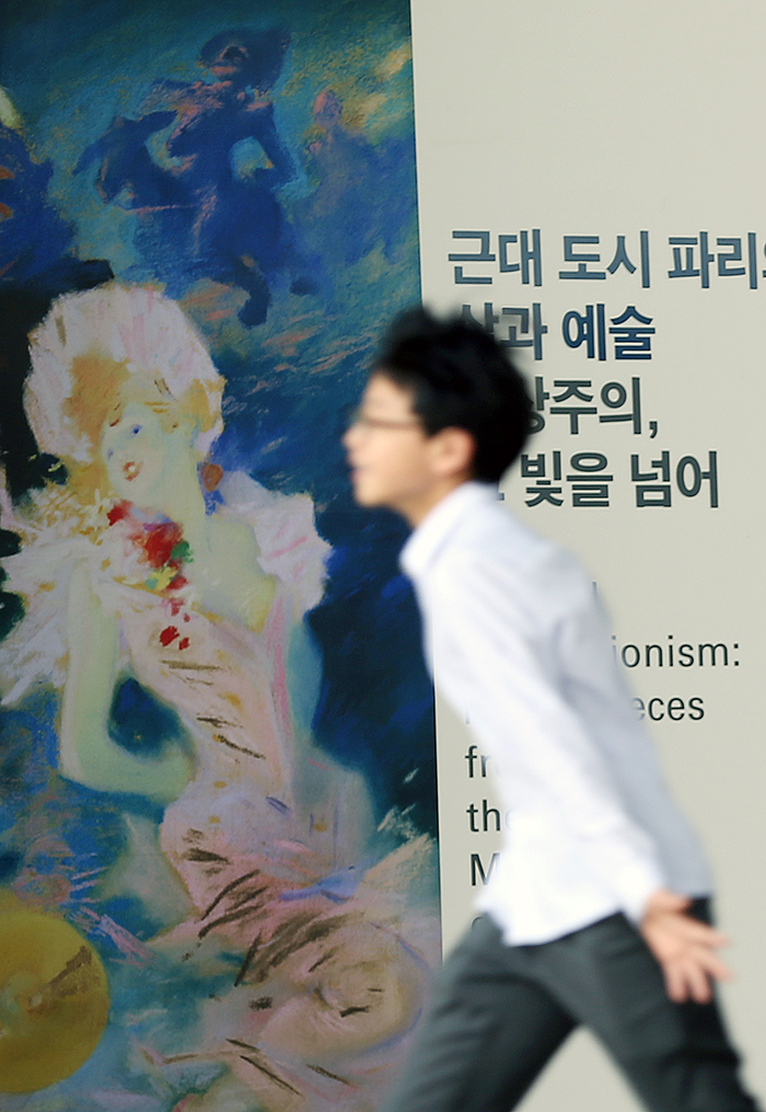 오르세미술관展의 포스터 앞을 지나는 관람객. 전시는 8월 31일까지 개최된다. (사진: 전한)