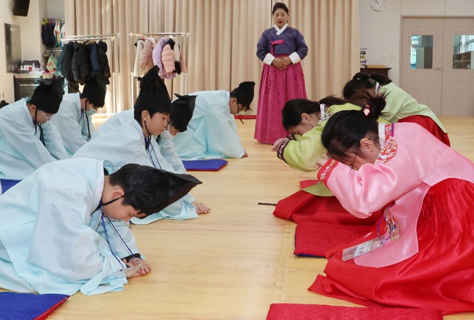 ひざまずいてお辞儀をする小学生たち