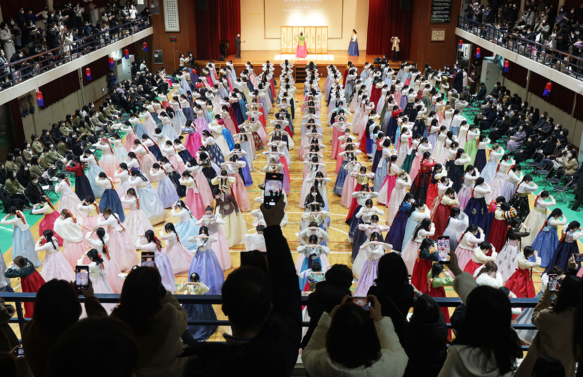 ７日、ソウル市内の女子高校で開かれた卒業式で、韓服を着た卒業生たちがひざまずいてお辞儀をしている。