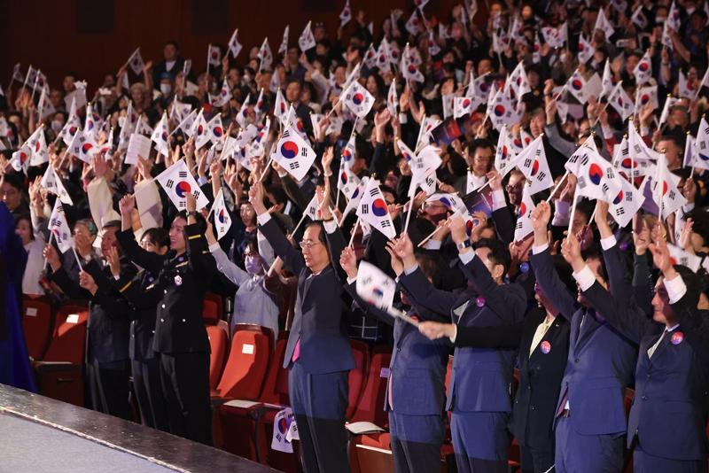 韓国の建国記念日にあたる「開天節」３日の午前、ソウル鍾路（チョンロ）区の世宗（セジョン）文化会館で開かれた第４３５５周年建国記念日の慶祝式で、政府の主要人物たちが太極旗を振りながら愛国歌を斉唱している。この日の行事には韓悳洙（ハン・ドクス）国務総理、国民の力の尹在玉（ユン・ジェオク）院内代表、共に民主党の洪翼杓（ホン・イクピョ）院内代表と市民など１５００人余りが参加した。