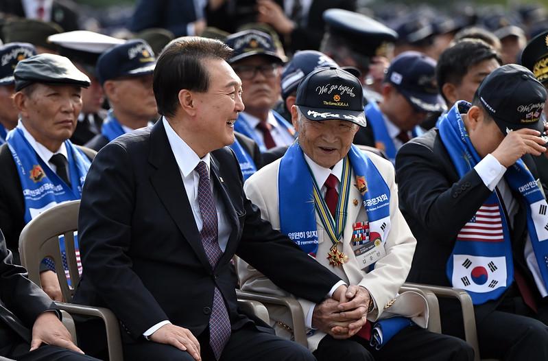 韓国戦争の参戦勇士キム・ウンソン氏の手をつないで話す尹大統領＝１２日、ソウル