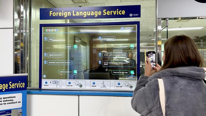 明洞駅にある「外国語同時対話システム」の写真を撮る、テュルキエから来た観光客のカルデレン・コーセー氏＝１２日、ソウル、チェ・ジンウ　