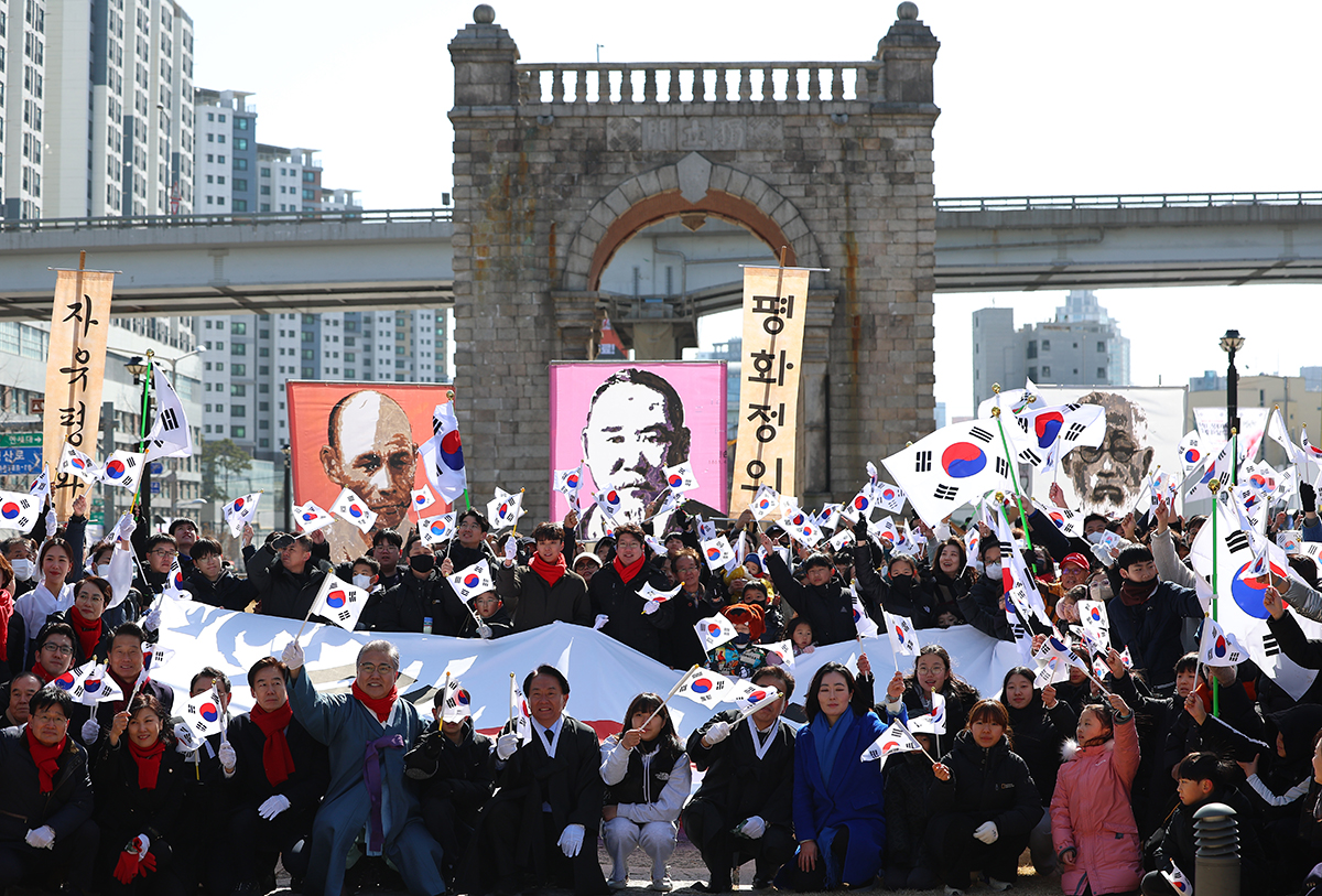 独立運動記念日「３・１節」を迎えた１日、ソウル・西大門区の独立門の前で、３・１独立万歳運動の再現行事に参加した人たちが「太極旗」を振りながら記念撮影をしている。