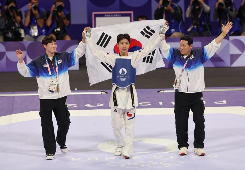 ２０２４パリ五輪テコンドー男子５８ｋｇ級の決勝戦で優勝した後、太極旗を手に喜ぶパク・テジュン（真ん中）＝７日（現地時間）、フランス・パリ