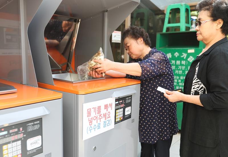 生ごみの量に応じて料金を支払う施設を利用して生ごみを捨てる様子＝聯合ニュース