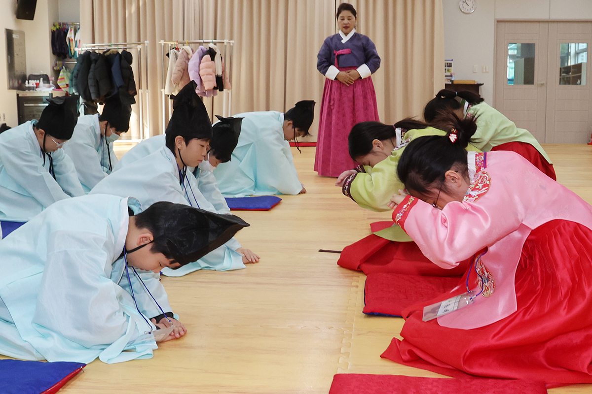 ６日、釜山市内の教育会館で伝統文化を体験するクラスが開かれ、韓服を着た小学生たちがひざまずいてお辞儀をしている。 
