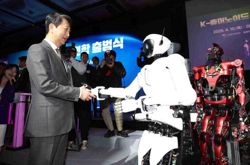 「Ｋ－ヒューマノイド連合発足式」で、ヒューマノイドと握手するアン・ドクグン長官（左）＝１０日、ソウル・中区 