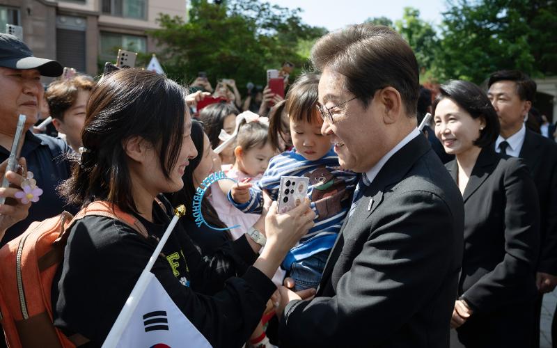 ４日、イ・ジェミョン大統領が仁川（インチョン）市にある私邸から国立ソウル顕忠院（ヒョンチュンウォン）に向かう前に住民たちと挨拶をする様子。