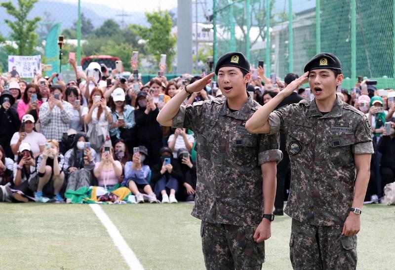 ファンと取材陣に向かって敬礼するＢＴＳのＲＭとＶ＝１０日、江原道・春川市、聯合ニュース