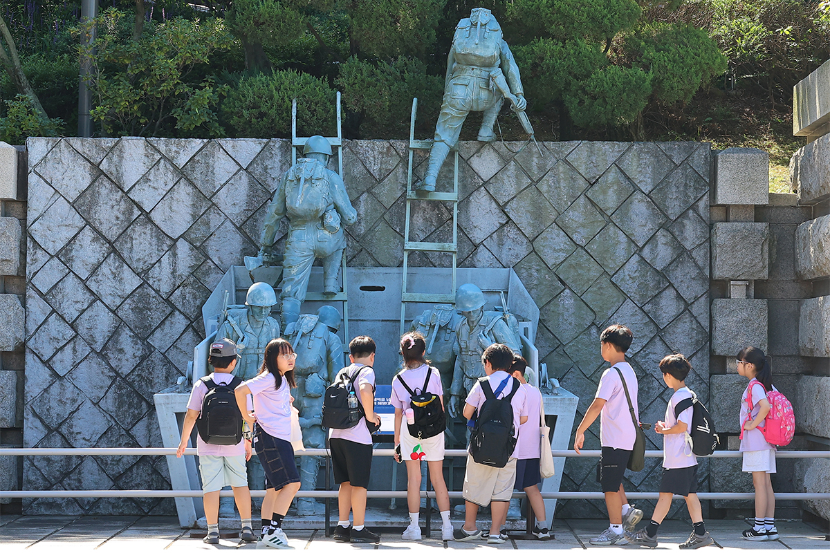 仁川（インチョン）上陸作戦７５周年の記念日を４日後に控えた１１日、仁川上陸作戦記念館を訪れ、海岸の防壁を越えて上陸する米海兵隊の兵士像を見学する小学生たちの様子。