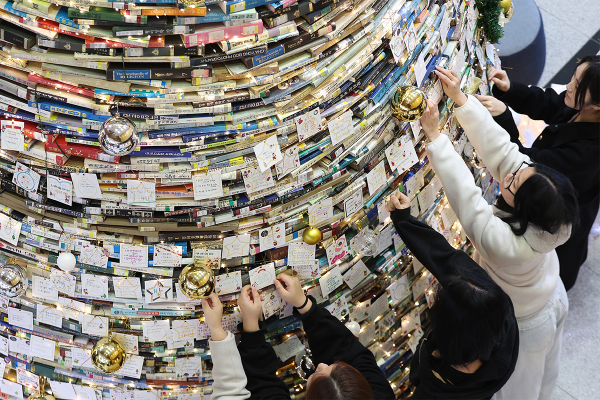 １６日、大邱（テグ）大学の慶山（キョンサン）キャンパスにある図書館で、ブックツリーに願い事をする学生たち。廃棄予定の約４０００冊の図書を活用し、高さ５メートル、幅３メートルのツリーが設置された。