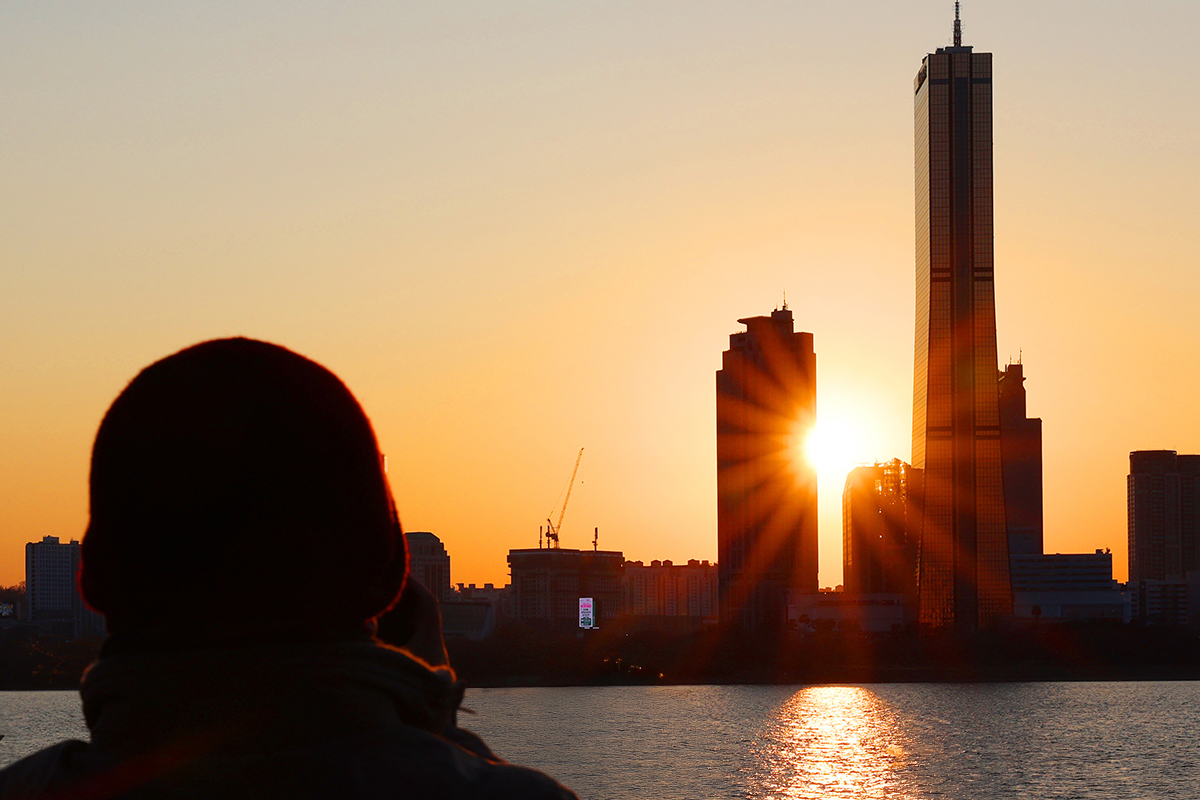 ３０日午後、ソウル・龍山（ヨンサン）区の二村（イチョン）漢江（ハンガン）公園で、赤く染まった夕焼けを眺めながら一年の終わりを迎える市民の様子。