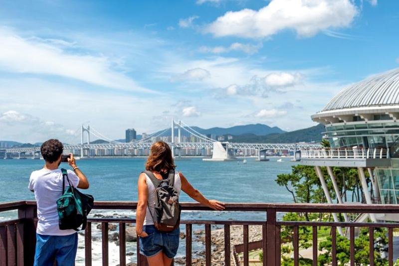 写真は、釜山（プサン）の東柏海岸散策路。釜山は「医療ウェルネス」と「海洋レジャー」を柱に発展する観光都市だ。海雲台や広安里の景色を楽しみながら医療サービスを受けられるメディカルツーリズムが、多くの外国人を魅了している。都市の活気と自然の安らぎを併せ持つ釜山は、世界的に注目される観光地である。