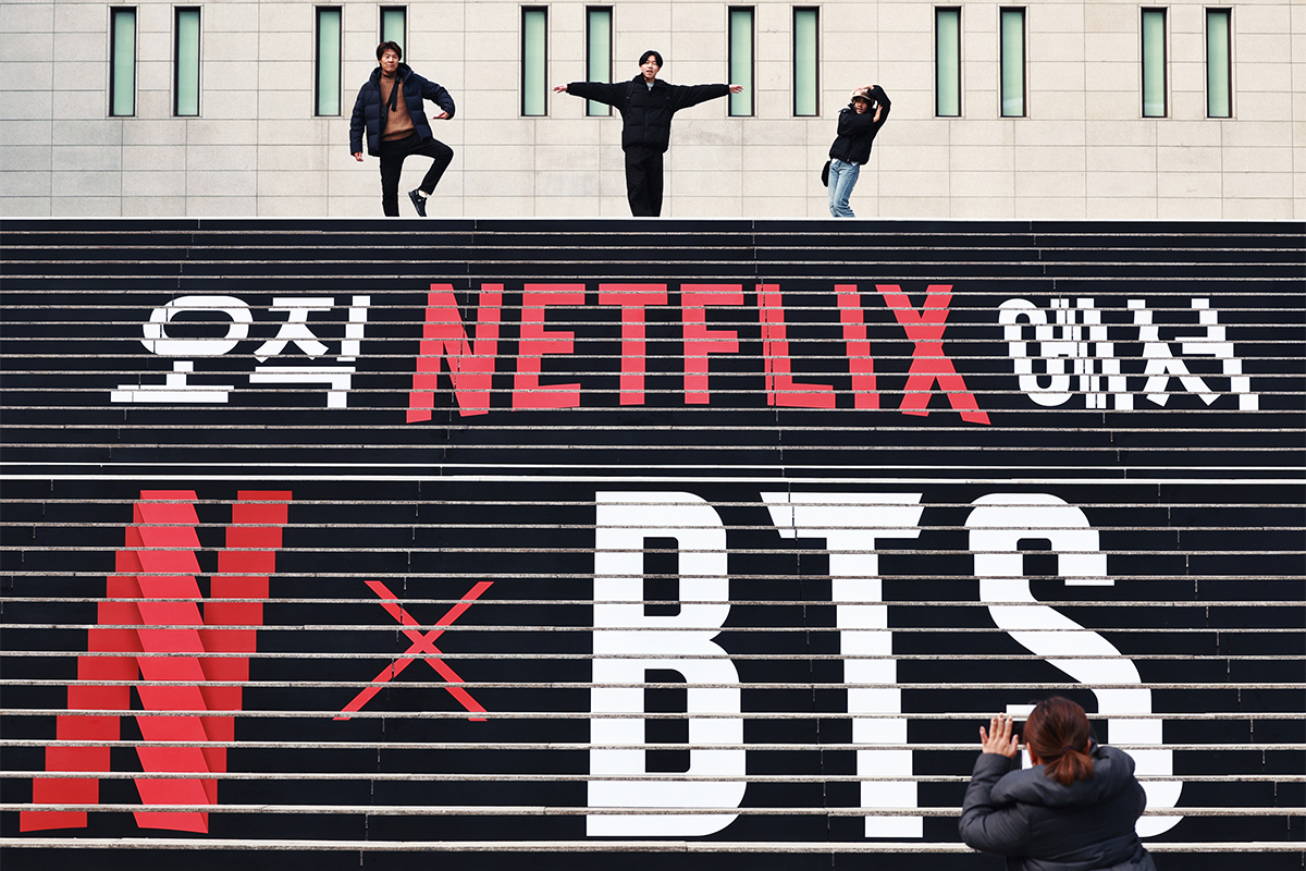 １１日、ソウル・鍾路（チョンノ）区にある世宗（セジョン）文化会館。階段には、ＢＴＳ（防弾少年団）の「完全体」復活を祝うラッピングが施されている。外国人観光客らは、階段の上でそれぞれお気に入りのポーズで記念撮影をしていた。