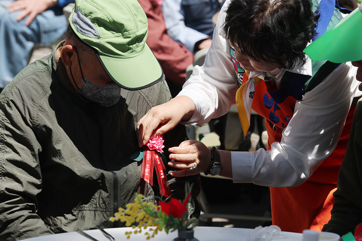 「両親の日」の８日、ソウル・東大門（トンデムン）区で「両親の日」のイベントが行われた。写真は、ボランティアたちが高齢者の胸にカーネーションを付けている様子。