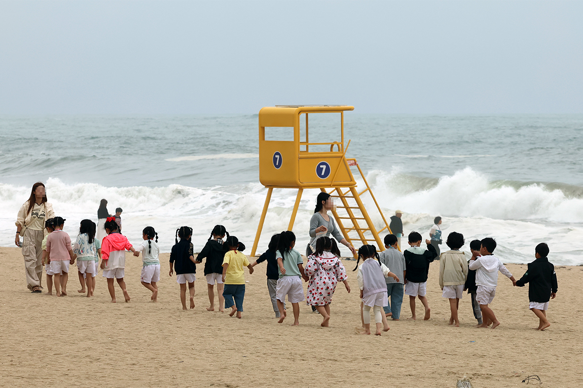 ２２日、江原道（カンウォンド）・江陵（カンヌン）市の鏡浦（キョンポ）海水浴場で、園児たちが先生に引率されながら、砂浜を歩いている様子。