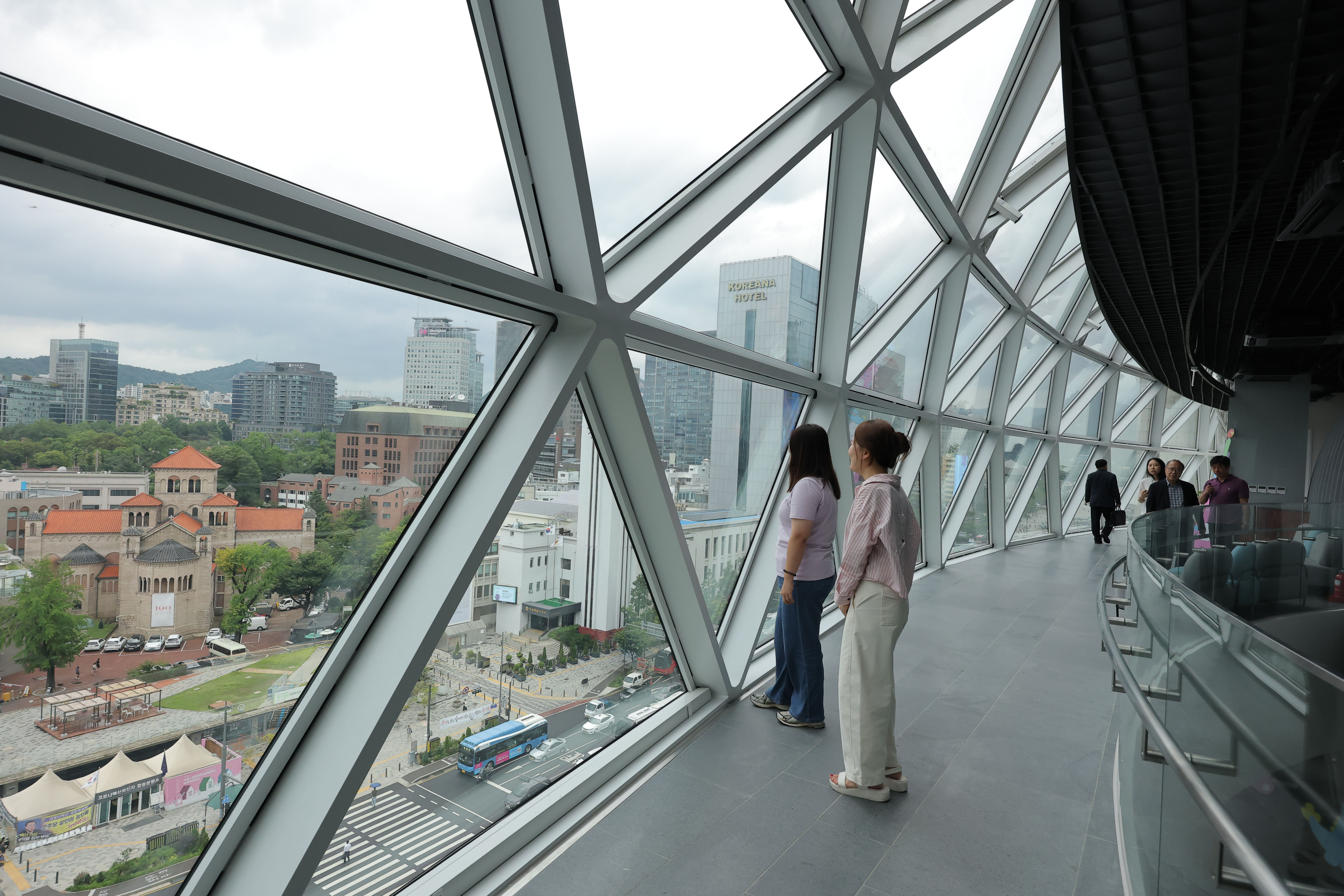 ６日、ソウル市庁舎西館の８、９階に「空展望台」が新たに設けられた。写真は、展望台からソウル中心部の街並みを眺める市民たち。